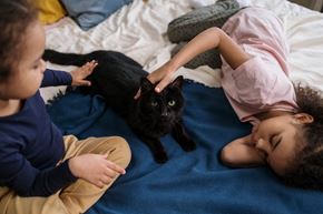 Amarillo apartment for rent - Two children playing with a black cat on a bed.