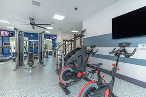 San Antonio apartment for rent - A gym with exercise equipment and a television on the wall.