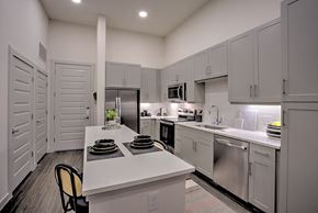 Dallas apartment for rent - A kitchen with white cabinets and a white island with plates on it.