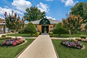 Longview apartment for rent - an exterior view of a brick building with a green awning and landscaping