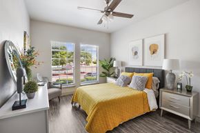 Round Rock apartment for rent - A bedroom with a yellow bedspread and a ceiling fan.