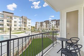 San Antonio apartment for rent - A balcony with a table and chairs overlooks a courtyard with a pool.