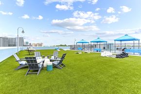 Atlanta apartment for rent - A lawn with chairs and umbrellas is in the foreground with a pool and apartment buildings in the background.