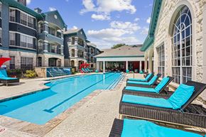 Round Rock apartment for rent - A large swimming pool with lounge chairs and a building in the background.