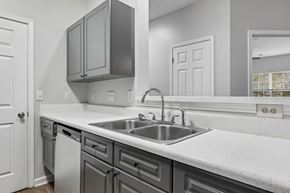Concord apartment for rent - A kitchen with a white counter top and grey cabinets.