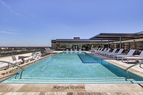 Austin apartment for rent - a swimming pool with white lounge chairs and a building in the background