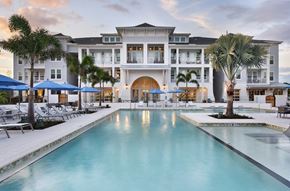 Fort Myers apartment for rent - a large swimming pool with palm trees in front of a building