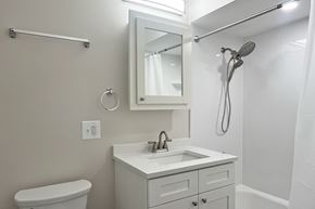 Forest Park apartment for rent - A white bathroom with a toilet, sink, mirror, and shower.