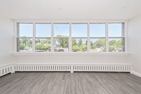 Kitchener apartment for rent - A room with a large window overlooking a street with trees and buildings.