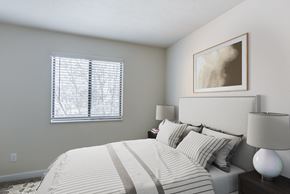 Valparaiso apartment for rent - A bedroom with a bed, a painting on the wall, two lamps, and a window allowing natural light in Valparaiso, IN.