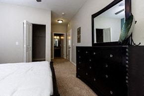 Merrillville apartment for rent - A bedroom with a large bed and a black dresser with a mirror above it.