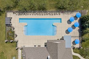 Merrillville apartment for rent - A large swimming pool surrounded by a concrete patio and blue umbrellas.