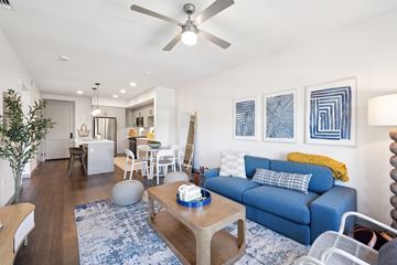 Oxnard apartment for rent - A living room with a blue couch and a ceiling fan.