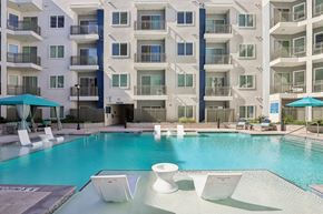 Las Vegas apartment for rent - A large white building with a pool in front. at Lura Vegas Apartments, Las Vegas, Nevada
