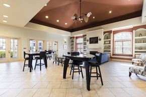 Kissimmee apartment for rent - Rapallo Apartments community clubhouse seating area with 2 bar tables and 2 chairs at each table.