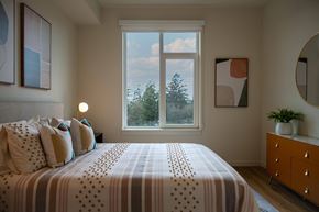 Tigard apartment for rent - Bedroom with patterned bedding and round mirror at Montage Apartments, Tigard, OR