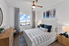 Oxnard apartment for rent - A bedroom with a large bed, a desk, and a ceiling fan.