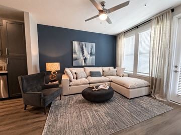 Kissimmee apartment for rent - A modern living room with a grey rug, a black chair, a white sofa, and a painting on the wall.