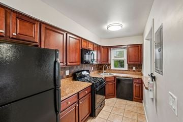 West Caldwell apartment for rent - A kitchen with brown cabinets and black appliances.
