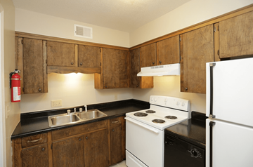 Liberty apartment for rent - A kitchen with wooden cabinets and white appliances.