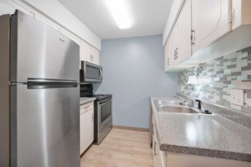 Riverside apartment for rent - A kitchen with a stainless steel refrigerator, microwave, and oven.