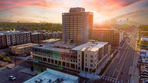 Denver apartment for rent - A cityscape with a large building in the foreground and a sunset in the background. at Denver Metro Village Apartments, Denver, CO