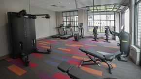 Denver apartment for rent - A gym with a variety of equipment including treadmills, weights, and exercise machines at Denver Metro Village Apartments, Denver, CO, 80204