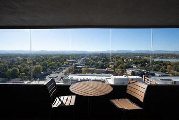 A view of a city from a high vantage point with two chairs and a table in the foreground.