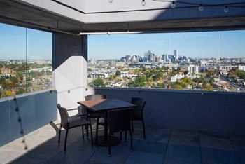 A table and chairs are set up on a patio overlooking a city.