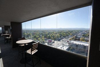 A table and chairs are on a balcony overlooking a cityscape.