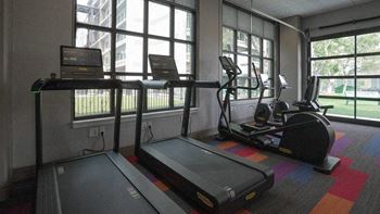 A treadmill and elliptical trainer in a room with large windows.