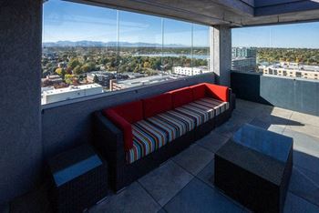 A red and striped couch sits on a balcony with a view of the city.