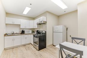 Chicago apartment for rent - A kitchen with a black stove top oven and white cabinets. at Academy at Drexel Apartments, Illinois