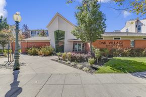Oakland apartment for rent - A building with a sign that says Oak Village is in front of some trees.