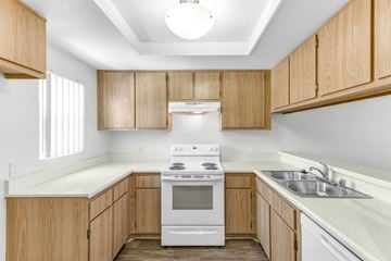 Escondido apartment for rent - A kitchen with wooden cabinets and a white stove top oven.