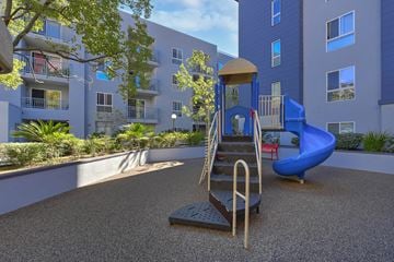 Los Angeles apartment for rent - A playground with a slide and a climbing frame in front of a building.