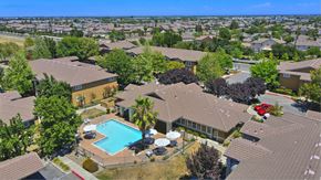 Sacramento apartment for rent - A bird's eye view of a residential area with houses, a swimming pool, and trees. at Hurley Creek Apartment Homes, Sacramento, CA, 95834