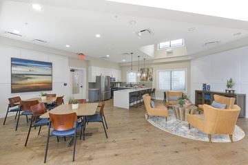 Alexandria apartment for rent - A spacious room with a dining table and chairs, a kitchen area, and a large painting on the wall.