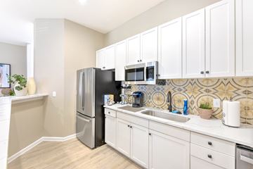 Irving apartment for rent - A kitchen with white cabinets and a black fridge.