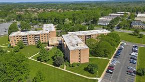 Edison apartment for rent - A parking lot is in front of a building with a green lawn in between at Menlo Manor Apartments, New Jersey, 08820
