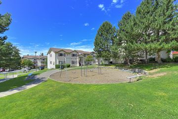 Kent apartment for rent - A playground with a swing set and a sandbox in the middle of a grassy area.