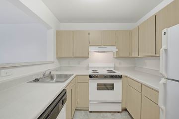 Sterling apartment for rent - A kitchen with a white stove top oven and white cabinets.