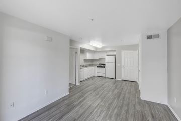 Corona apartment for rent - A kitchen with white cabinets and a countertop is visible from the living room.