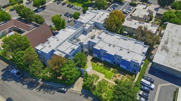 Costa Mesa apartment for rent - A parking lot with cars and a building with a blue roof.