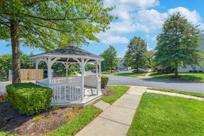Sterling apartment for rent - A white gazebo with a black roof is surrounded by greenery and a sidewalk at Acclaim at Sterling in Sterling, Virginia