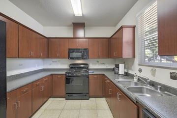 Rocklin apartment for rent - A kitchen with brown cabinets and a black stove top oven.
