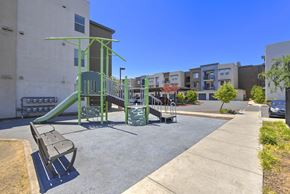 Sacramento apartment for rent - Playground area with green equipment and seating at Anton Arcade Apartments, Sacramento, 95825
