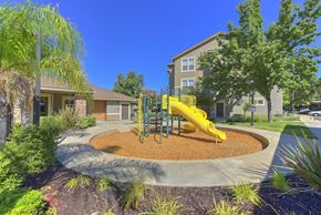 Rocklin apartment for rent - Playground with yellow slide and wood chip safety surface at Whitney Ranch Apartments, California, 95765
