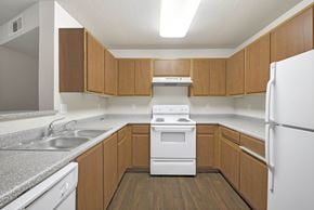 Sacramento apartment for rent - A kitchen with wooden cabinets and a white refrigerator at Hurley Creek Apartment Homes, Sacramento