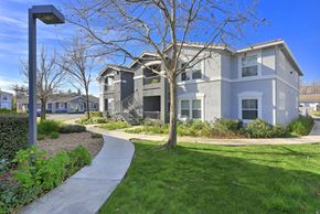 North Highlands apartment for rent - Apartment buildings with curved walkway and landscaping at Corsair Park Senior Apartments, North Highlands, CA 95660